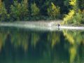 Un pecheur au bord d'un joli lac vert